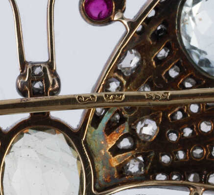 Брошь из желтого и белого металла, общим весом 24,0 грамма, содержит природные вставки